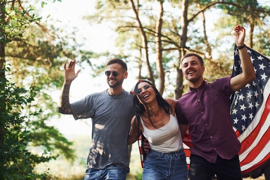 three-friends-celebrating-in-sunlight-holding-flag-2026-03-24-03-21-05-utc